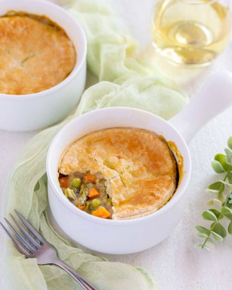 Small white dish holding one serving of Vegetarian Pot Pie with part of the crust removed to show filling